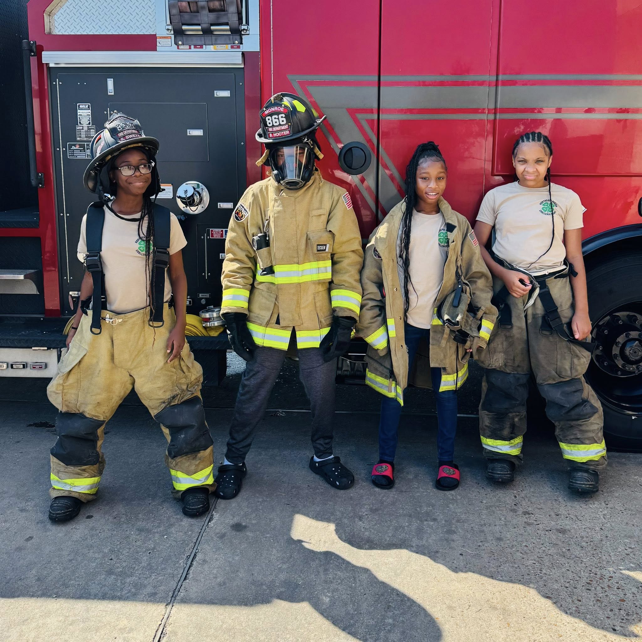 Four kids partially dressed in real firemen's gear.